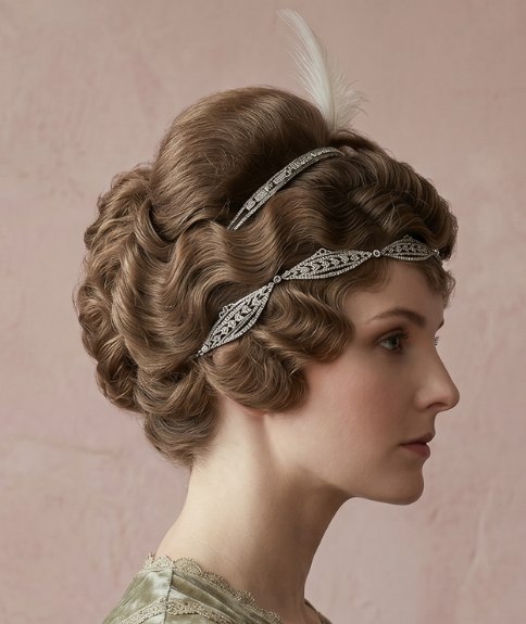 Opsteekkapsel uit de jaren 1910 met een hoofdband en een veer
