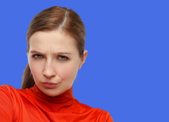 Vrouw met een glad oranje truitje en een slechte haarkleur