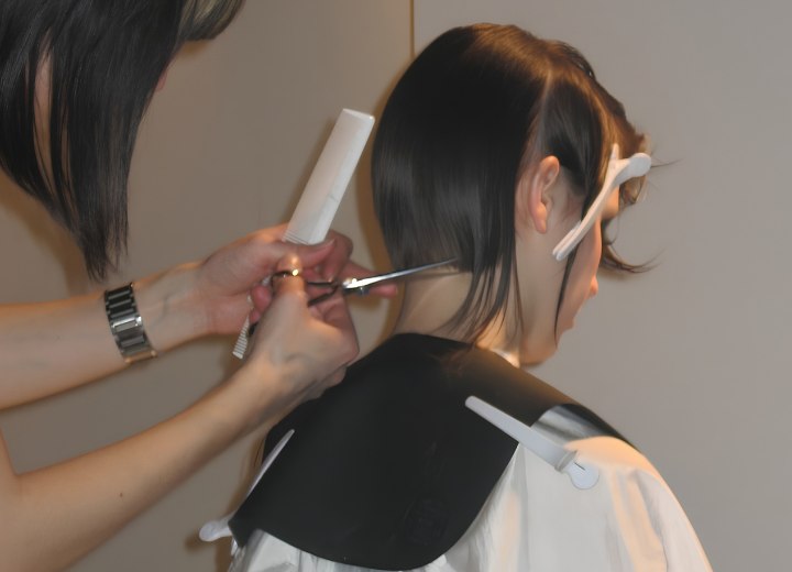 Kapster bezig met het knippen van haar