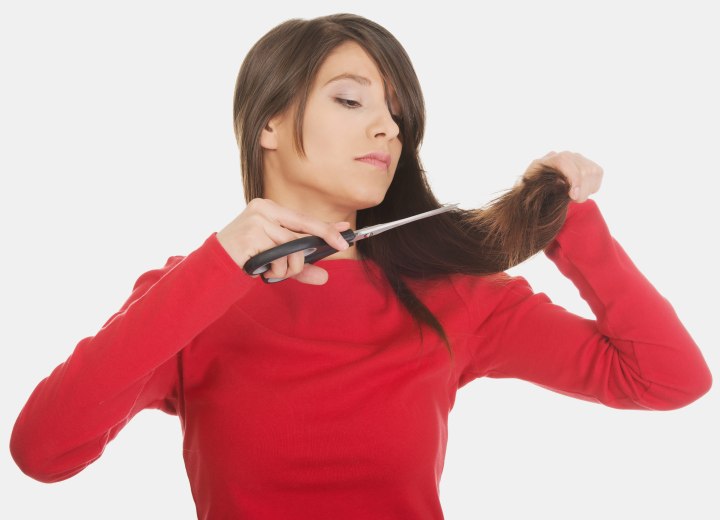 Vrouw die haar eigen haar knipt met een huishoudschaar