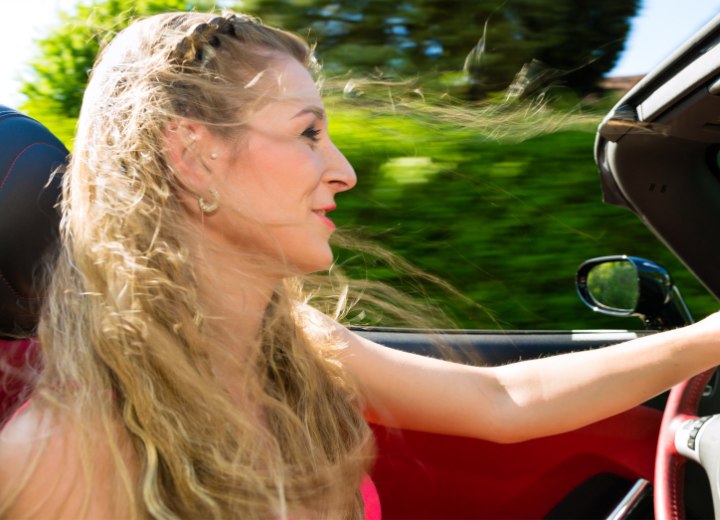 Vrouw met losse wapperende haren in een cabrio