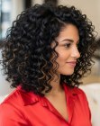 Donker krullend schouderlang haar met highlights